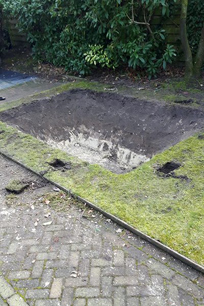 Rechthoekige kuil uitgegraven in het gazon voor een verdiepte trampoline