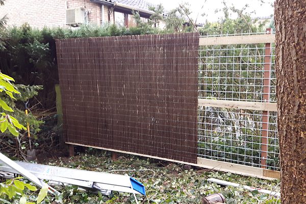 Rietmatten worden op een houten frame aangebracht als erfafscheiding