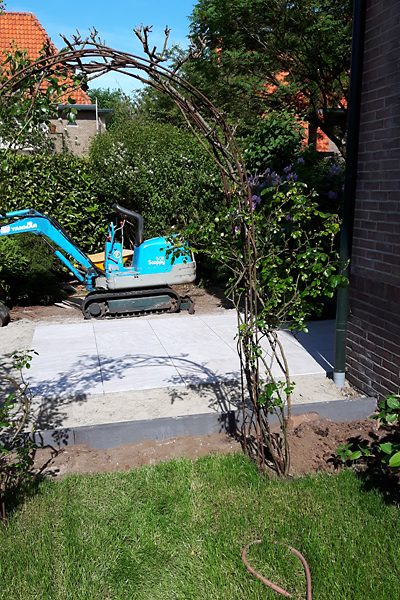 Nieuw aangelegd terras met minigraver ernaast tijdens de tuinaanleg